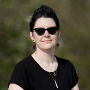 A person with short dark hair wearing sunglasses