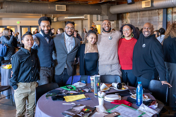A group of people standing in front of a decorated tabling, smiling for a group photo.