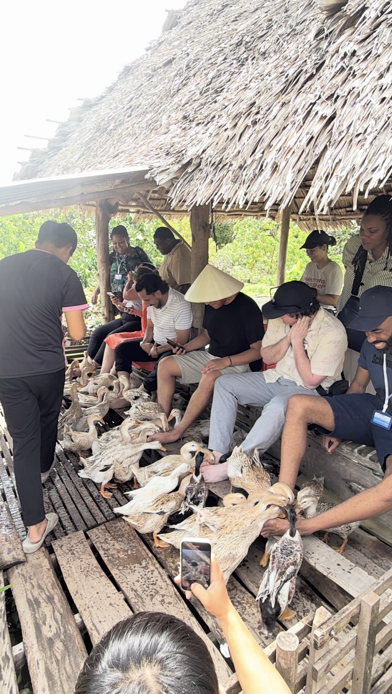 Students feeding ducks with their feet and smiling at the Farm in Vietnam.