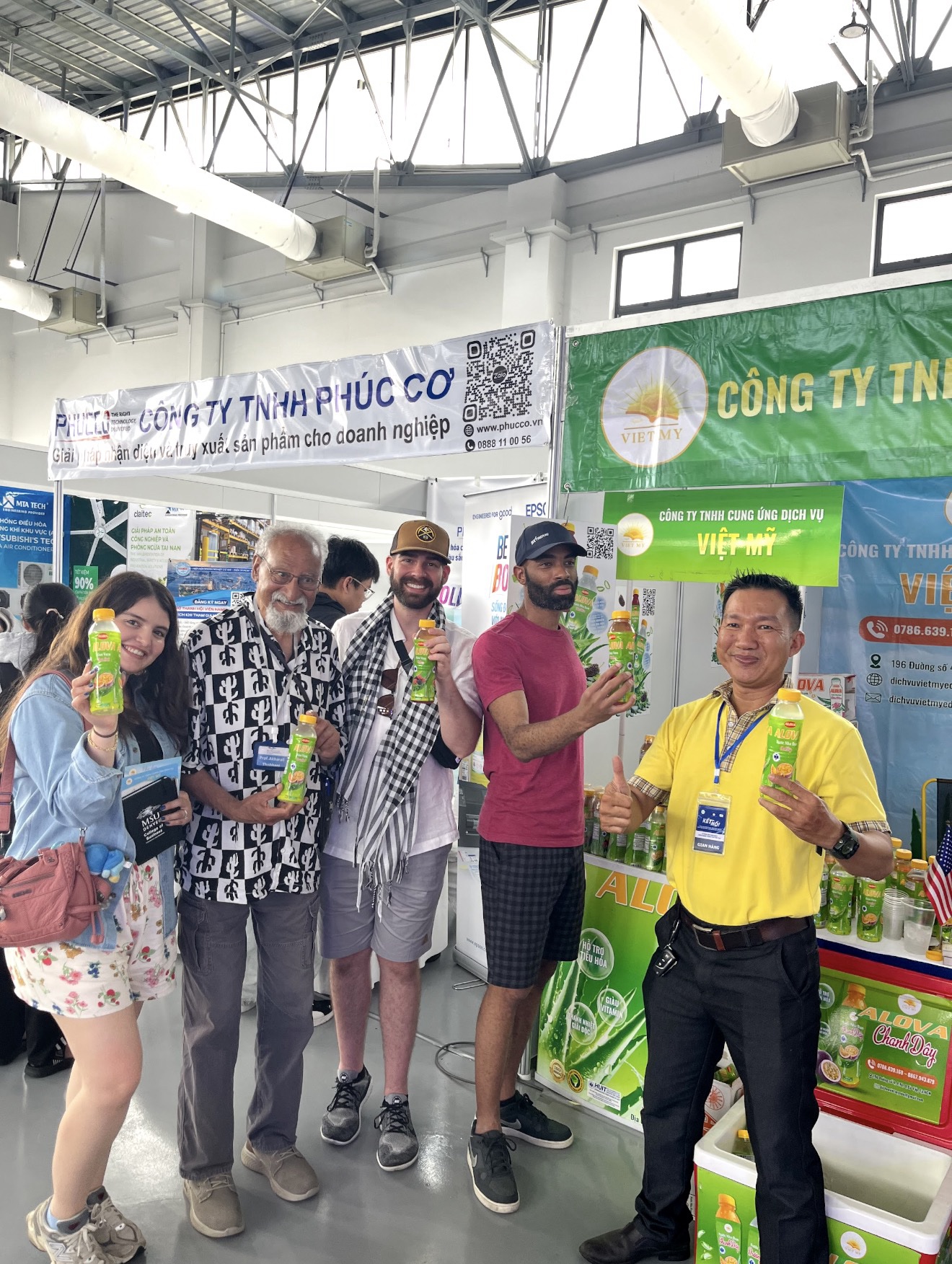 Students smiling with the owner of the juice they are holding in Vietnam.