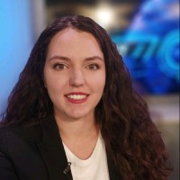 A woman with dark wavy hair wearing a black blazer
