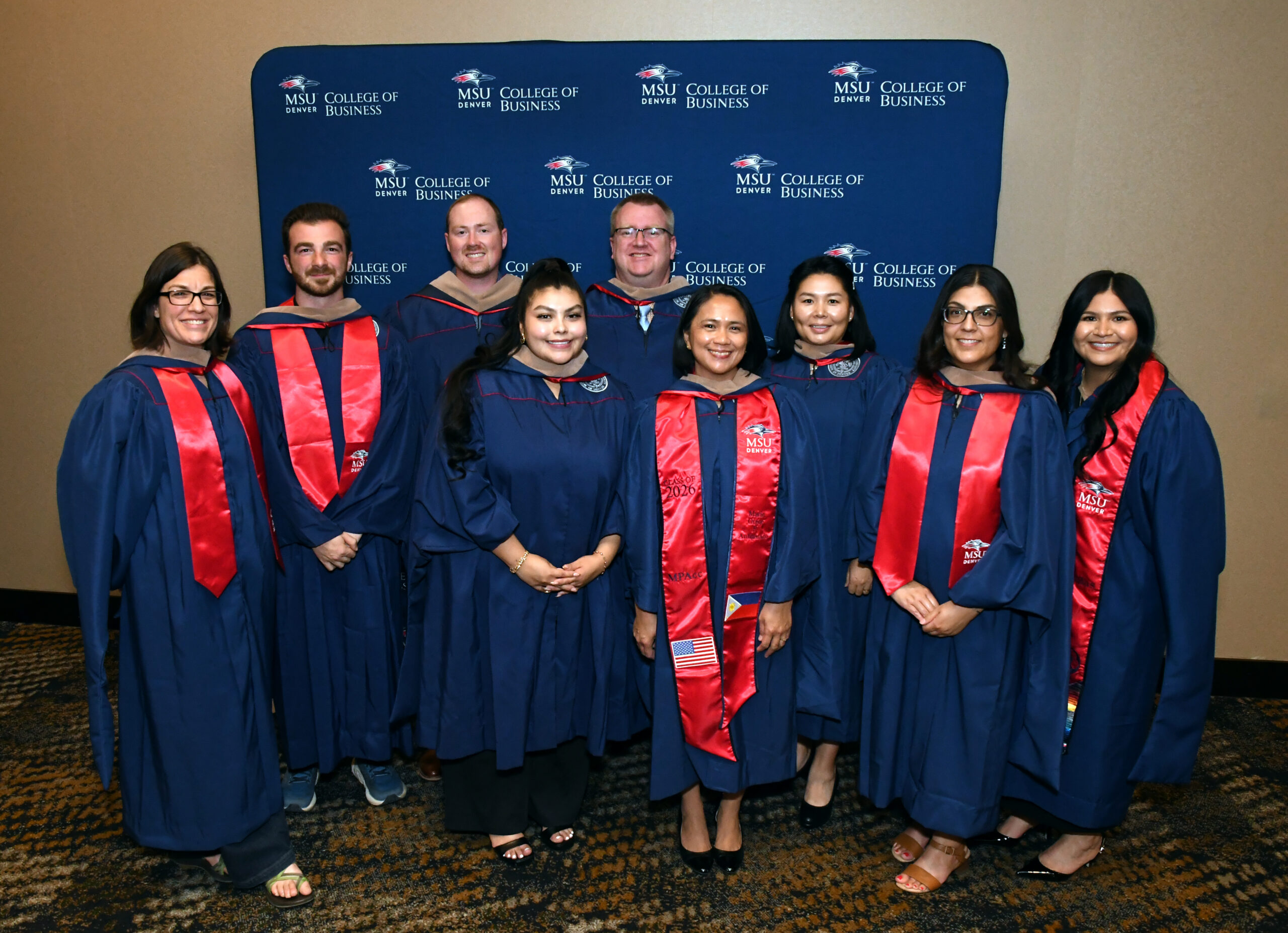 9 MPAcc grads in regalia smiling at the SP'26 MBA & MPAcc Hooding Celebration