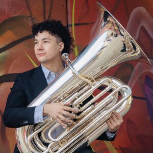 A man with dark hair holding a tuba