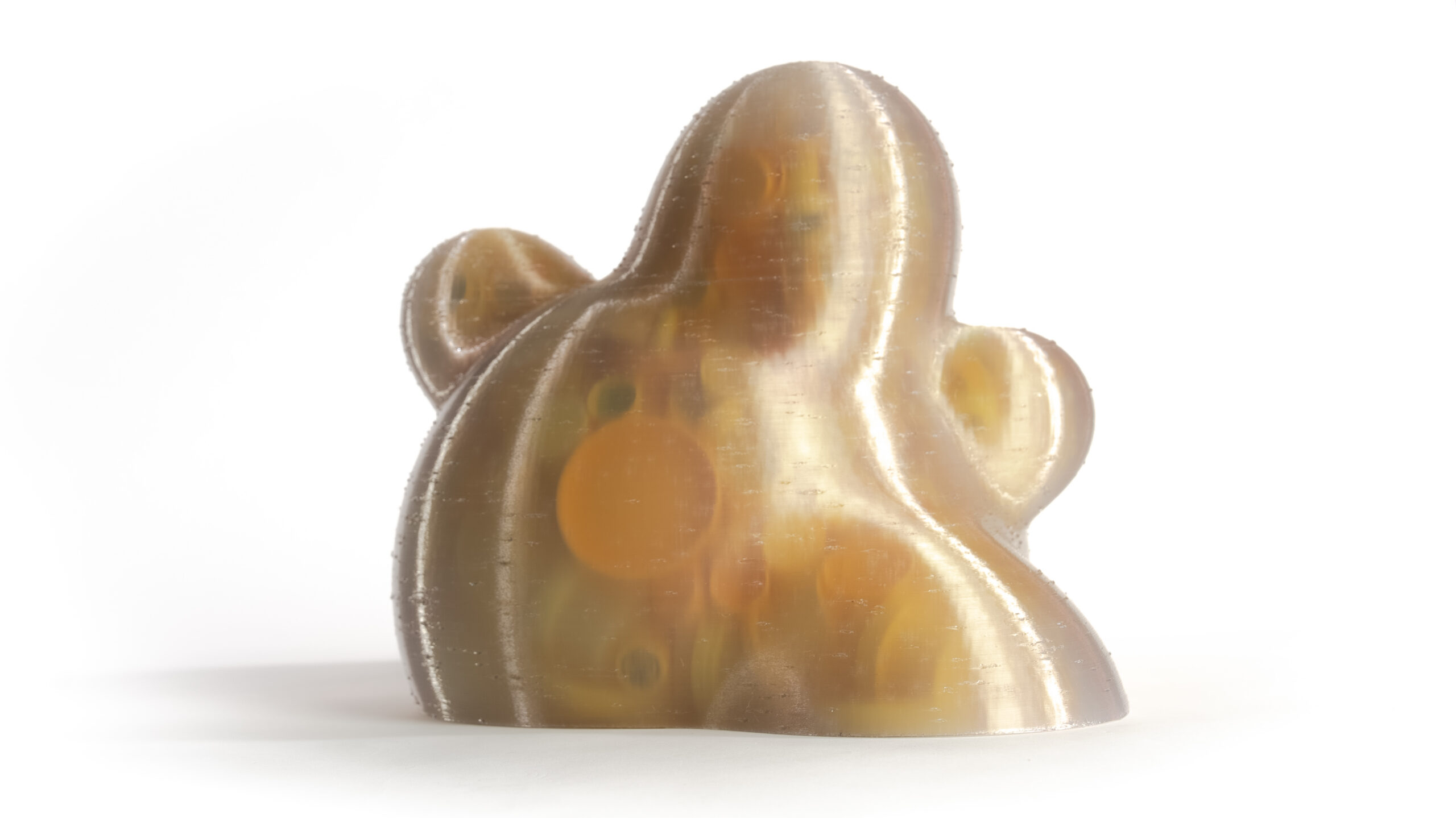 A glossy, golden, dome-like sculpture with rounded protrusions set against a white background.