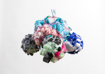 Cluster of colorful fabric bundles wrapped in netting against a white background.