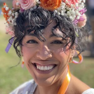 A woman with curly brown hair wearing a flower crown
