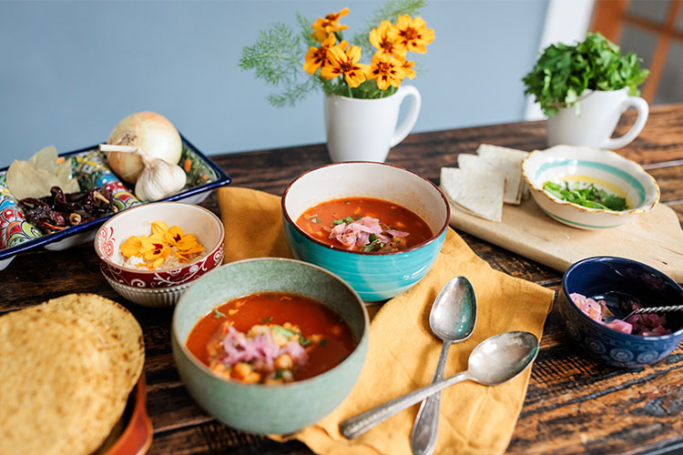 A set dinner table, tortilla soup with sides.