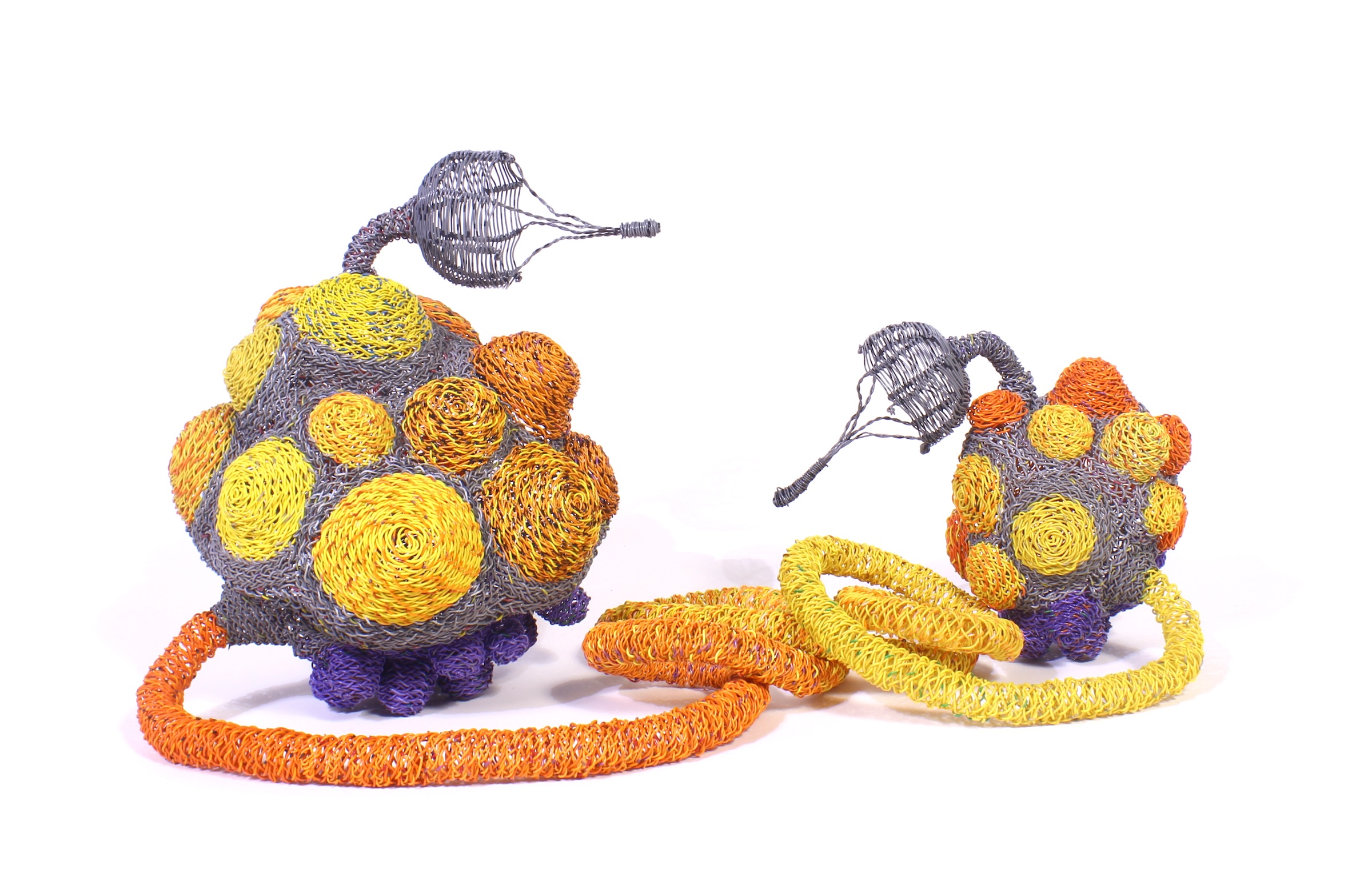 Two spherical wire sculptures with orange and yellow spiral patterns connected by a coiled loop.