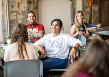 A round table surrounded by people of different ethnicities, actively conversing and sharing ideas.