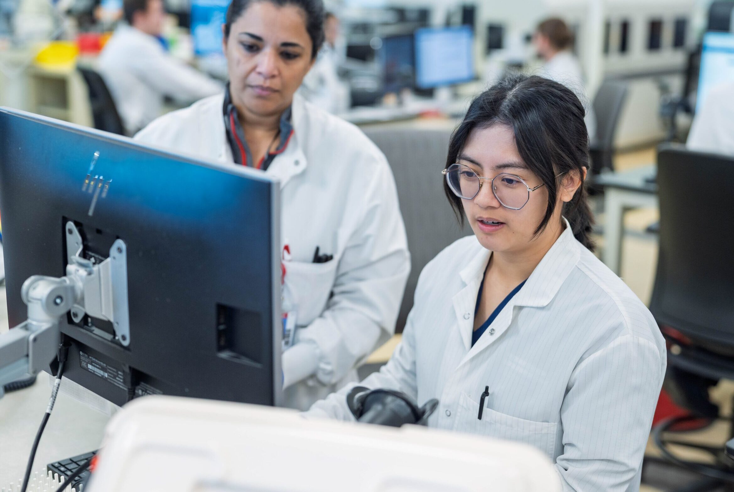 Two scientists in a hospital reviewing data on a monitor.