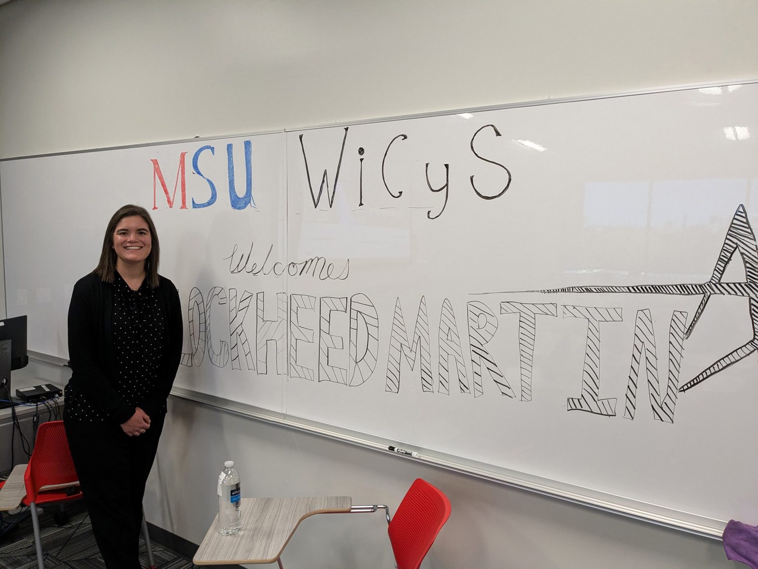 Guest speaker posing for a picture in front of the whiteboard