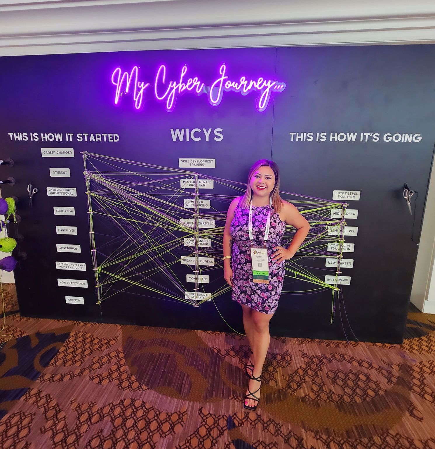 Women standing in front of background at the Women in Cybersecurity Conference in Dallas, TX