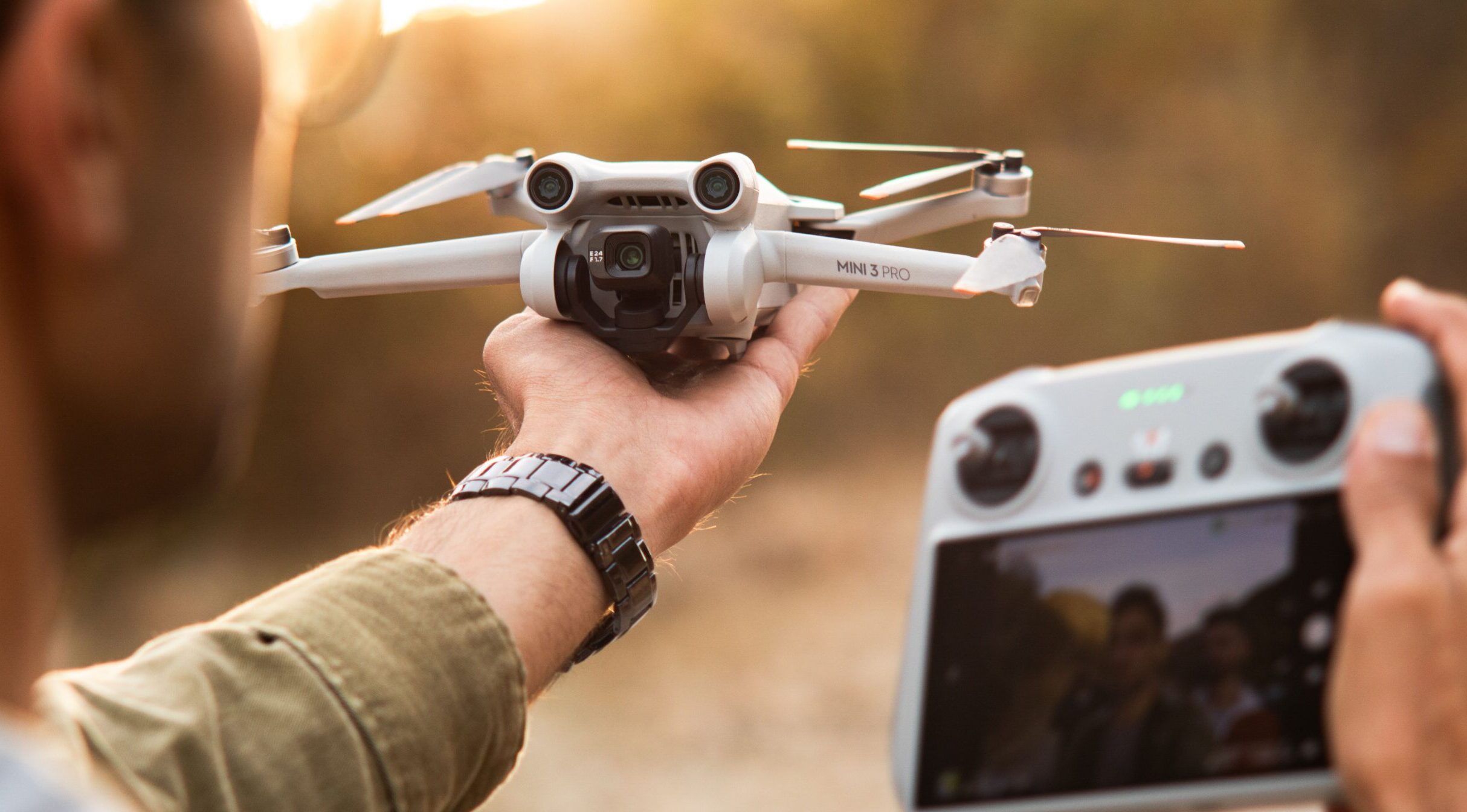 A person holding up a drone and drone controller outside.