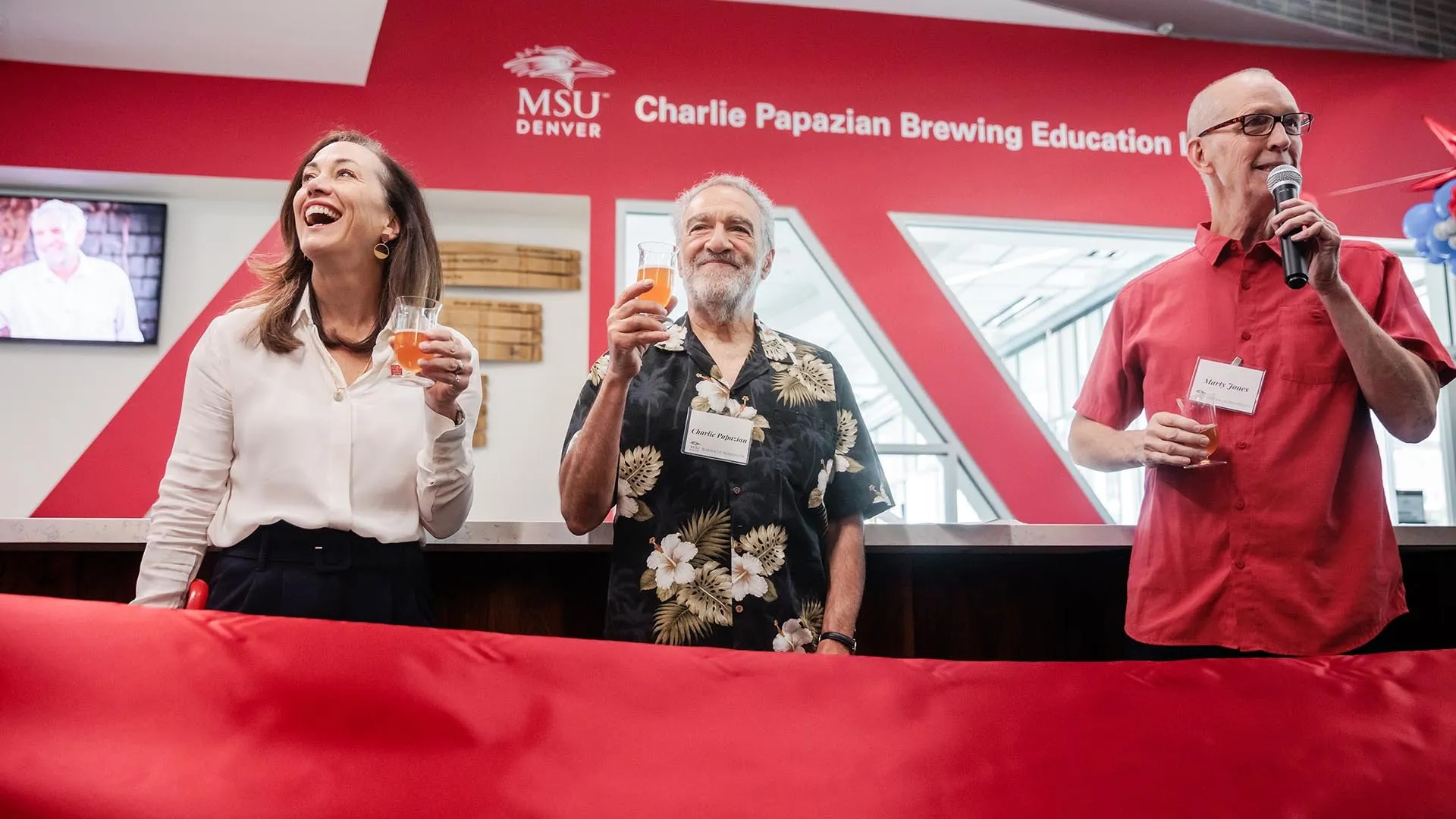Charlie Papazian, center, raises a glass with MSU Denver President Janine Davidson, Ph. D., and Marty Jones at the opening of the Charlie Papazian Brewing Education Lab in the University's School of Hospitality. Photo by Alyson McClaran