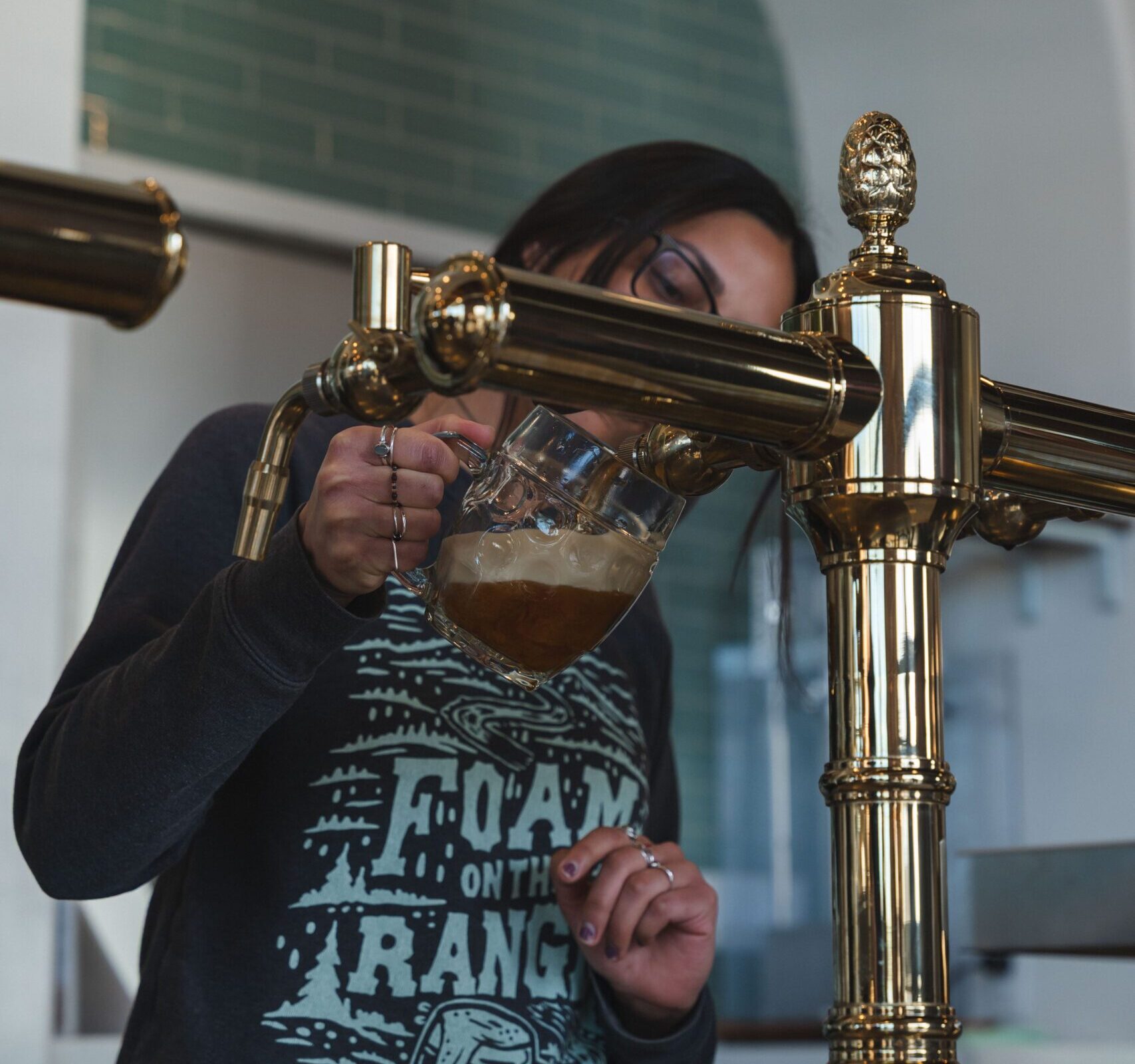 brewer pours a beer from a tap