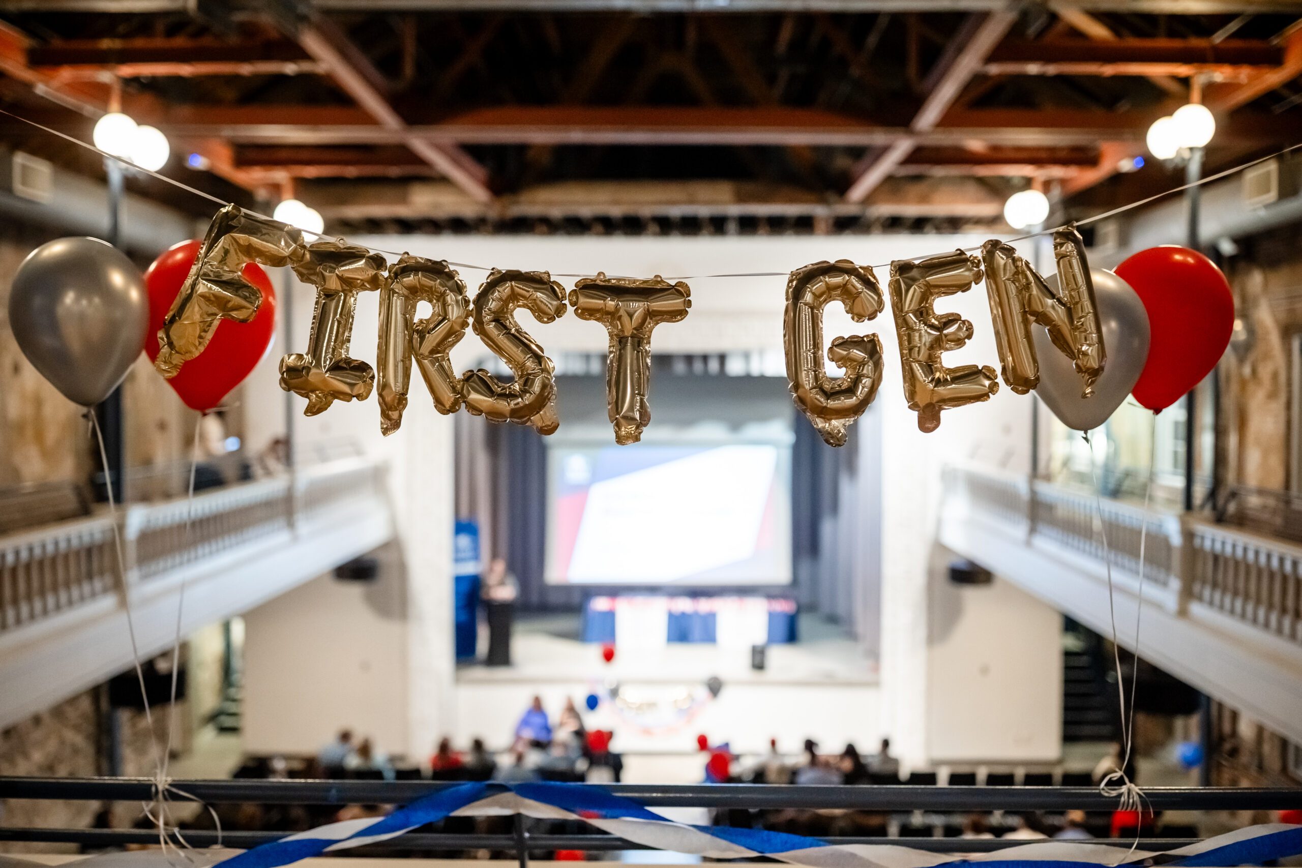 Metallic ‘FIRST GEN’ balloon letters displayed with blue and red balloons at the First Generation Celebration event