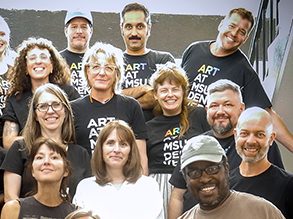 Group photo of members of the Department of Art, standing in a stairwell and smiling.
