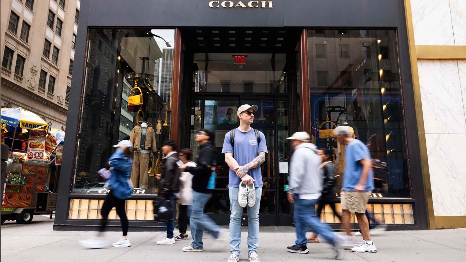 Outside the Fifth Avenue Coach store in New York City, Weldon Henderson holds the first pair of shoes he designed for the luxury brand, Coach.