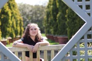 Woman with long hair has her arms over a fence
