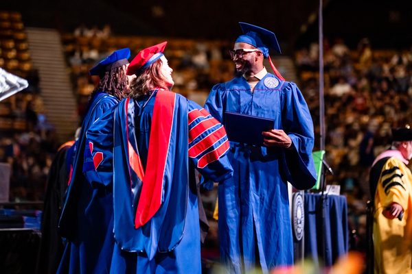 A grad shakes hands with MSU Denver President, Janine Davidson, Ph.D.