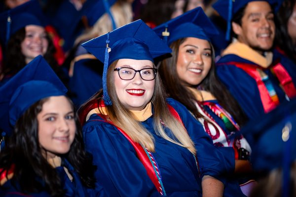 Several graduates smile excitedly as they await the start of the Spring 2026 Commencement ceremonies