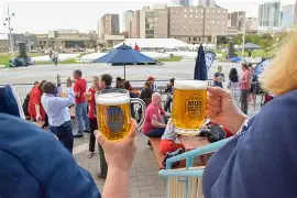 People holding mugs of beer on the Tivoli Quad patio