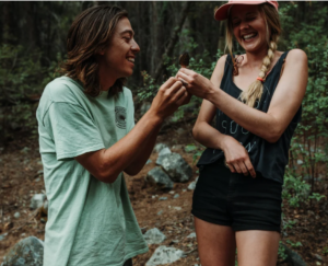 Photo of Tylor and Danielle Bereth smiling while holding a mushroom in a forest.