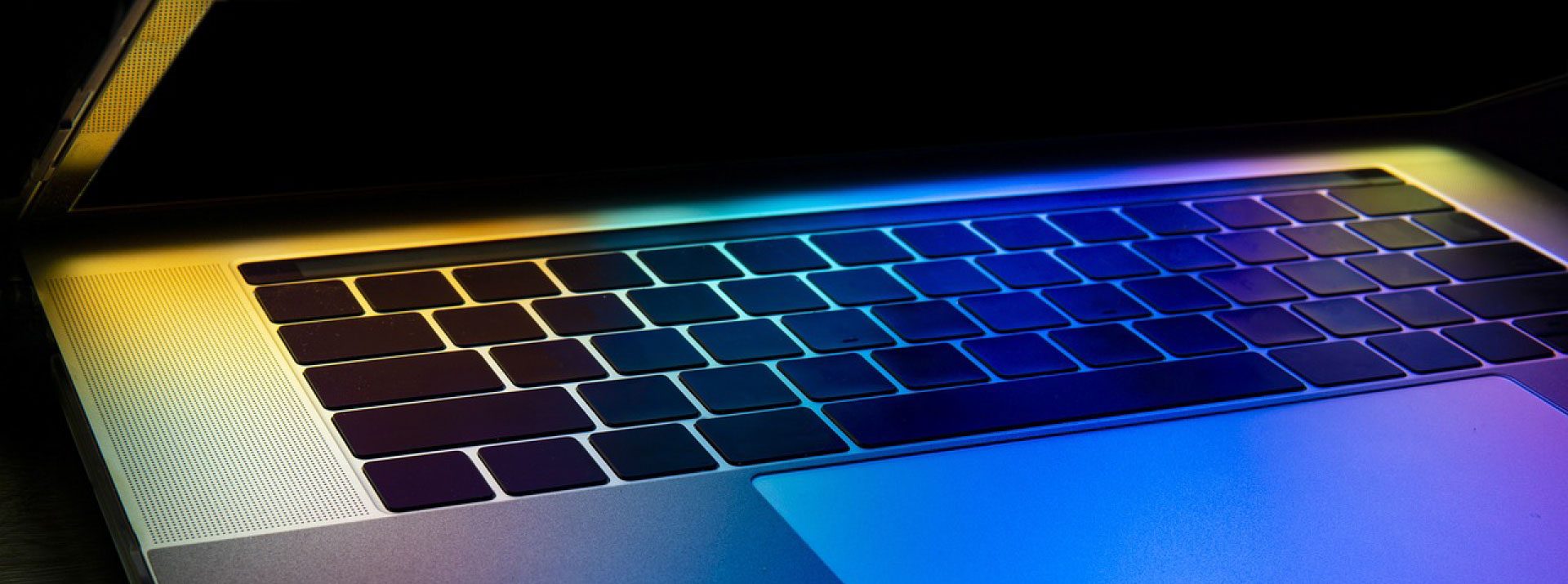 Closeup of laptop keyboard with various colors reflecting from it