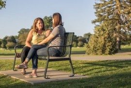 Two women chatting on a bench on campus