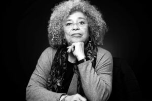 Black and white portrait of Angela Davis resting her chin on her hand and looking toward the camera.