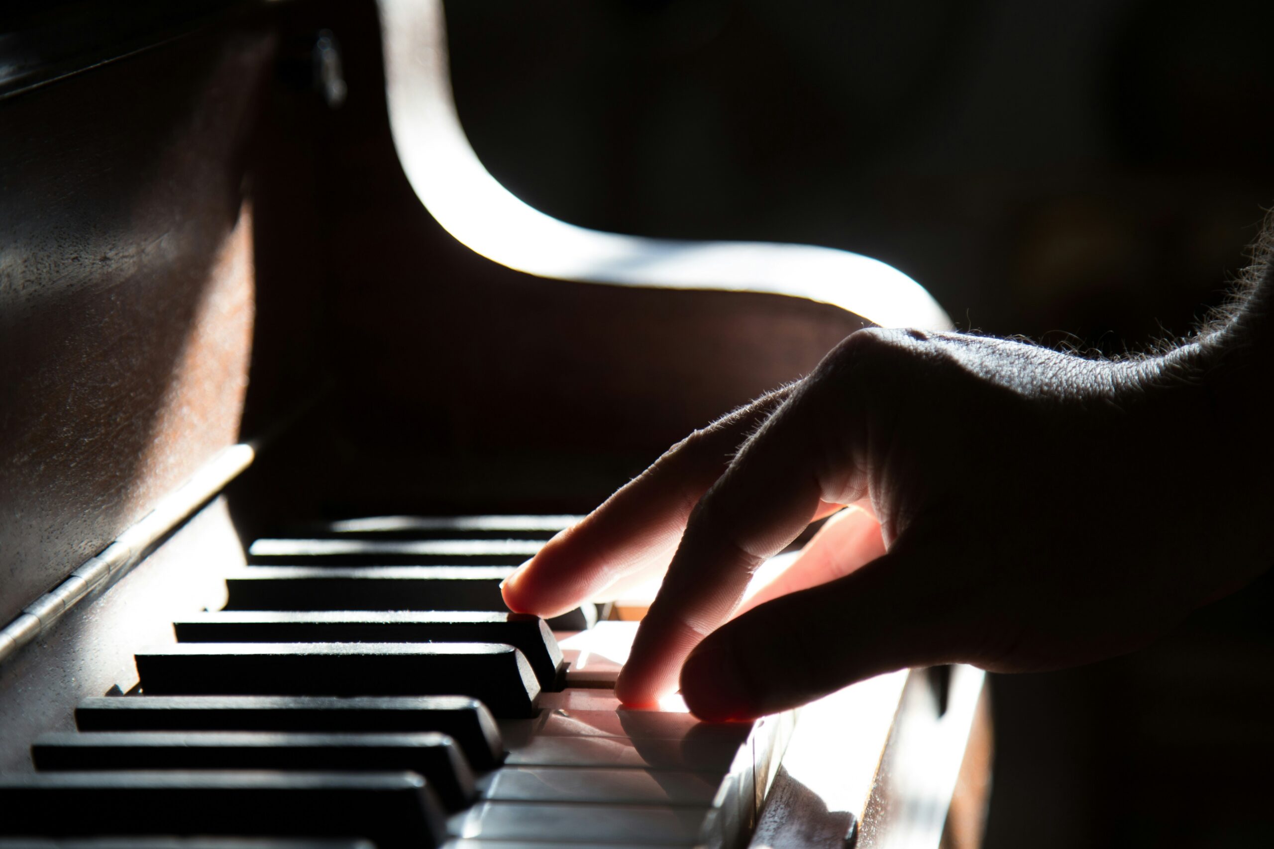 Close up of a hand pressing keys on an upright piano