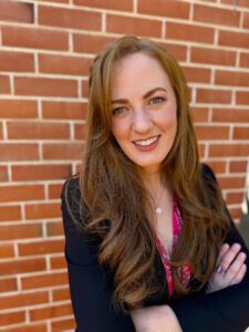 professional headshot standing in front of brick wall