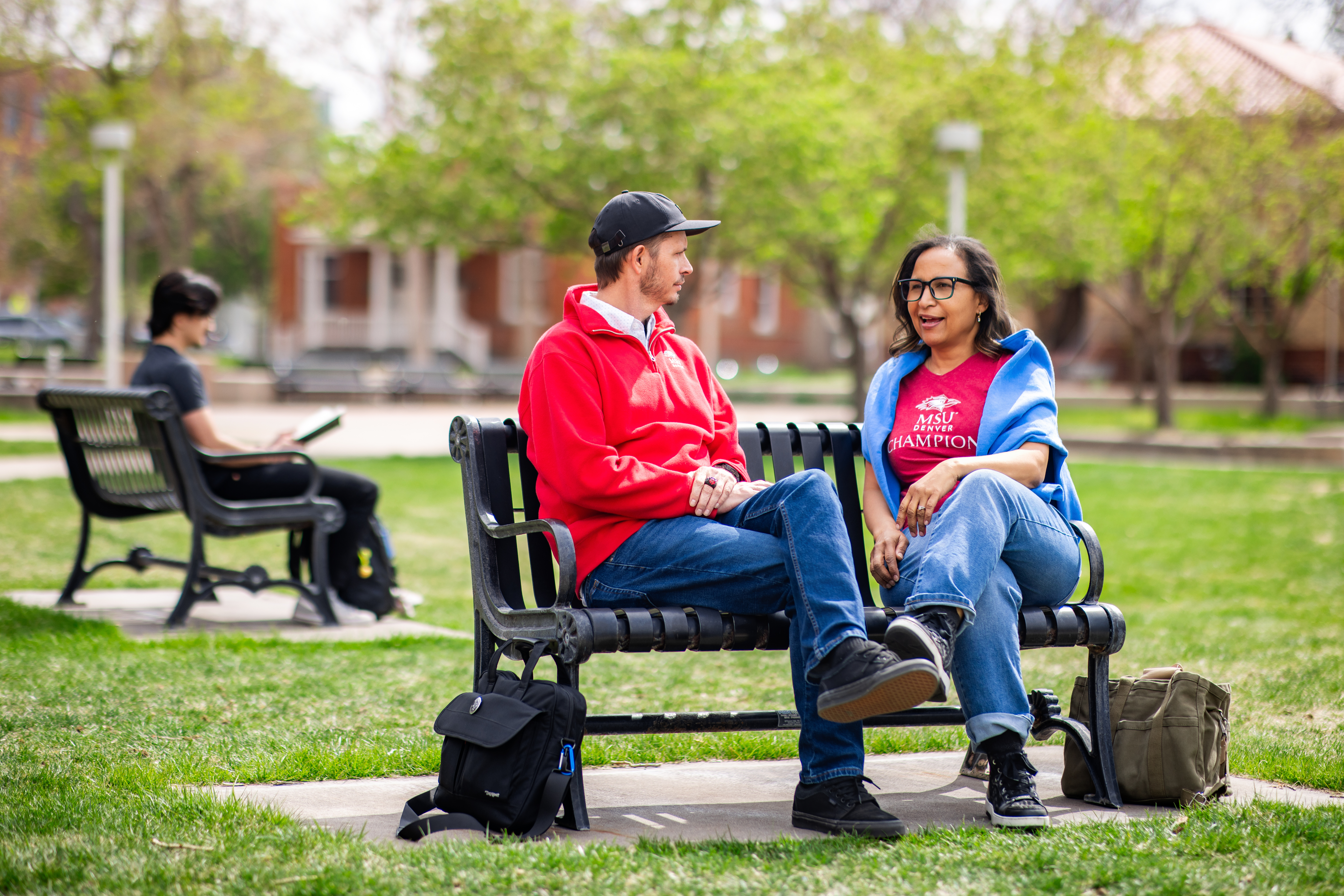 Two students sitting on a bench in a park