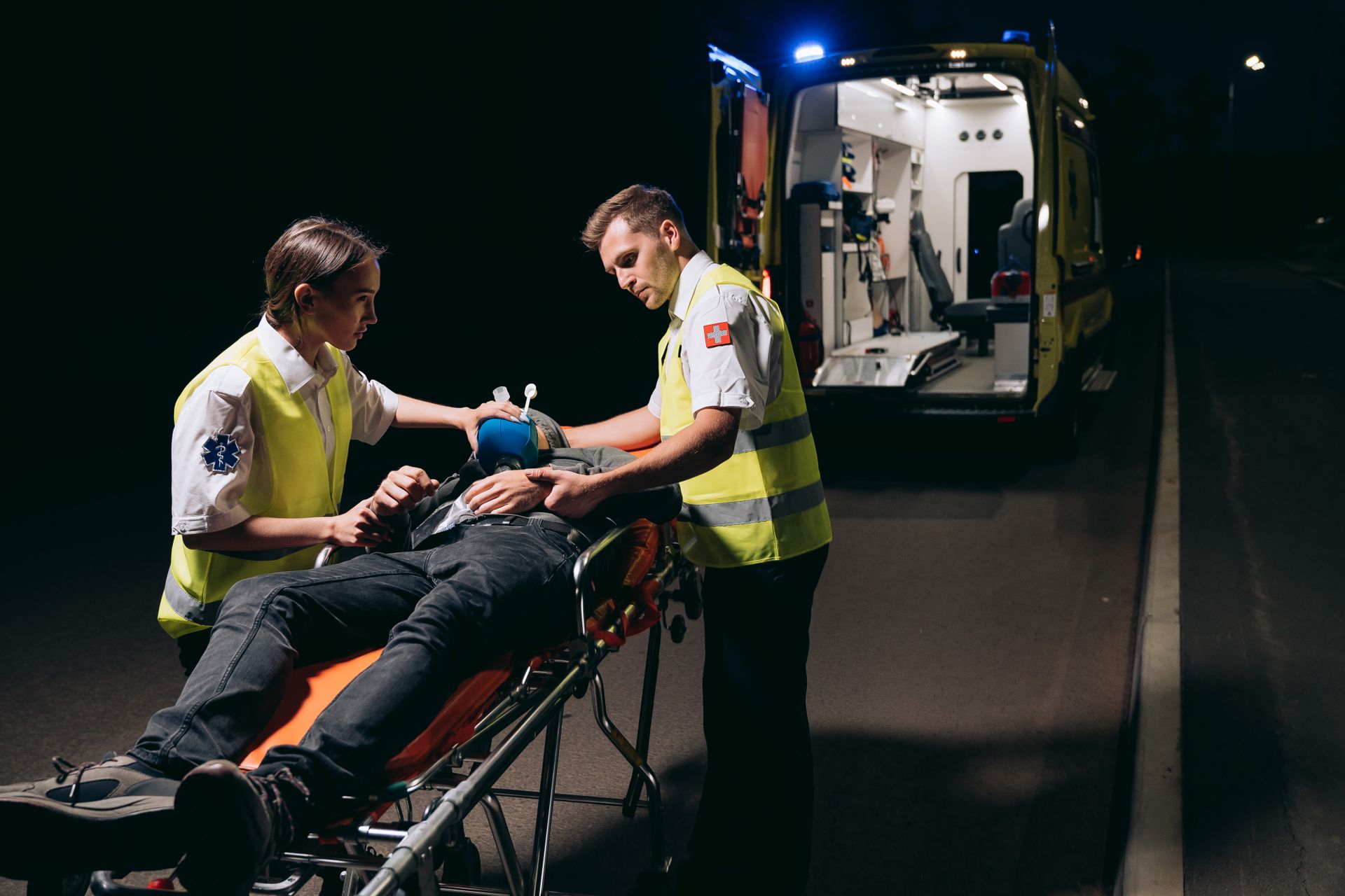 Two EMTs helping a patient on a stretcher.