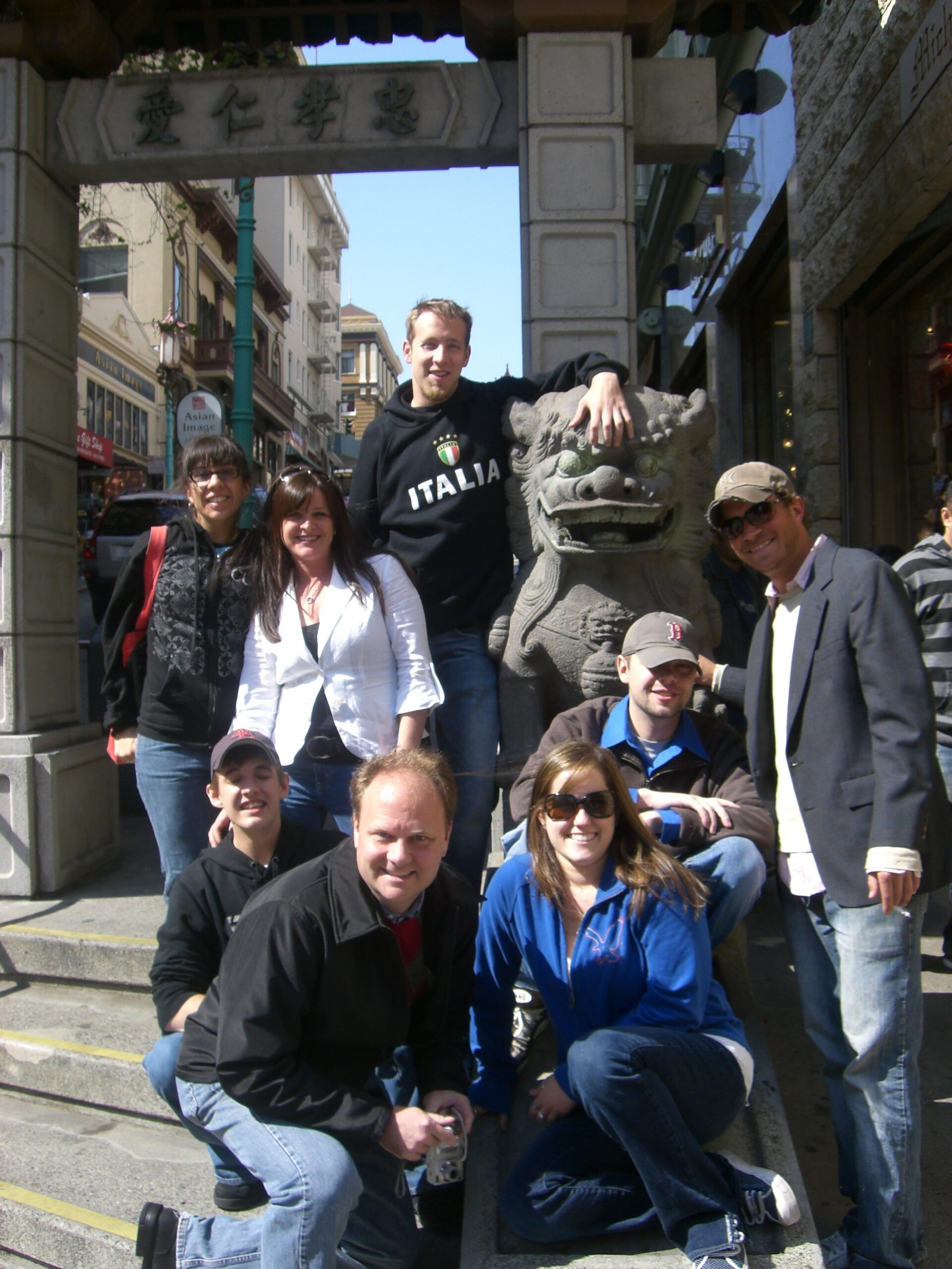 Richard Moeller and eight Model UN students in 2008, posing beside a stone lion statue beneath a gate inscribed with the Chinese characters 忠孝仁愛.