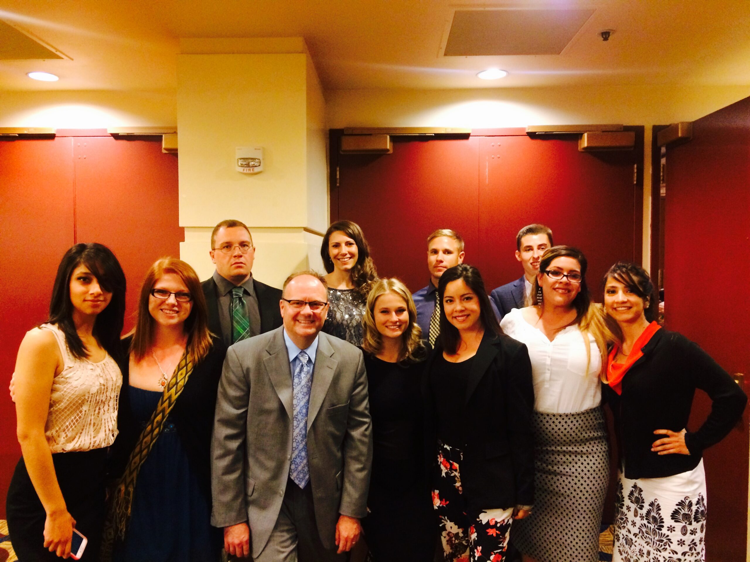 Richard Moeller and ten Model UN students in 2015, dressed in business attire and posing together in a hotel hallway.
