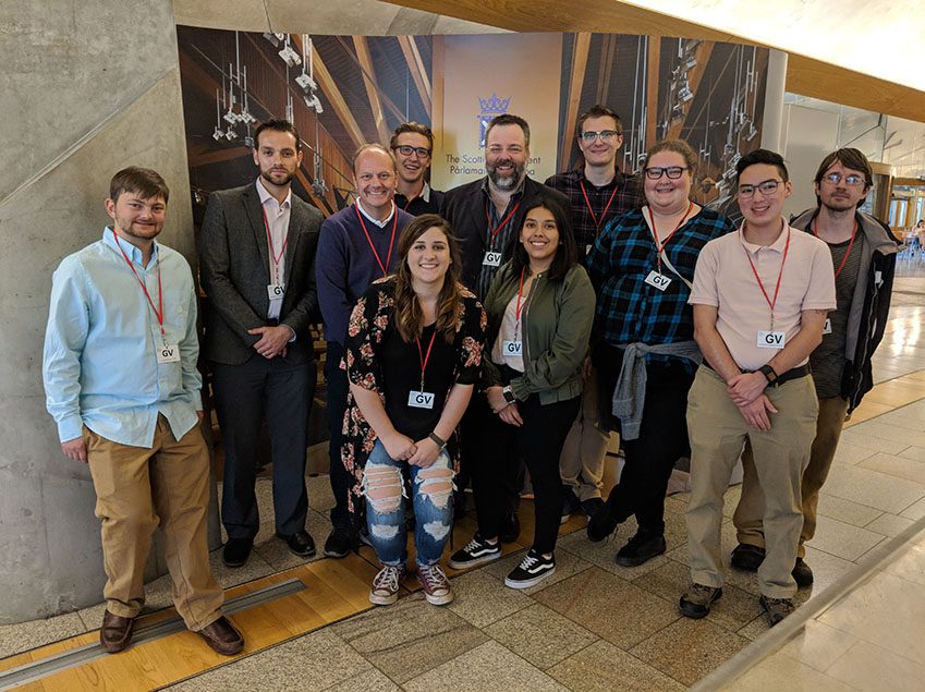 Richard Moeller and a group of Model UN students in 2018, wearing lanyards with badges reading 